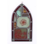 Stained glass panel, the arched panel made up with fragments to include a flower and Gothic text,