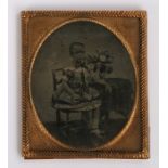 19th Century sixth plate ambrotype, of a boy seated in a dress by a bunch of flowers