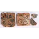 Two 13th Century tiles and two fragments of tiles. a whole Griffin / dragon example, a flower