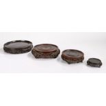 Four carved Chinese stands, each of circular form with fret carving, 24cm diameter to 9cm