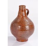 17th Century style pottery Bellarmine jug, in brown glaze with a bearded mask above a crest, 20cm