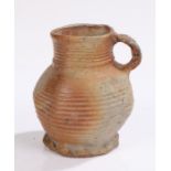 14th/15th Century stoneware jug, having a ribbed bulbous body and crimped foot with loop handle,