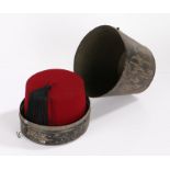 19th Century tin fez hat box, with a hinged lid and tapering body, together with a Fez, (2)