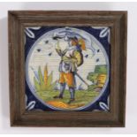 18th Century Delft tile, of a solider standing with a flag and a sword in it's hilt, housed within a