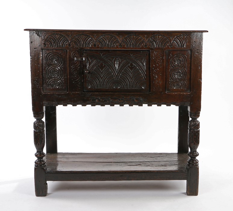 Mid 17th Century oak joined standing livery cupboard, the rectangular top above a lunette carved