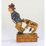 Carved wooden and painted toy in the form of a man and dog, with press button action, 19cm high