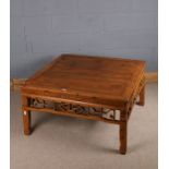 Chinese softwood low table, the square top above a pierced fret carved frieze and raised on square