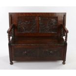 20th Century oak monks bench, the back carved in relief depicting figures within a tavern, hinged