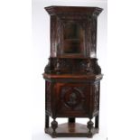 Victorian carved oak standing corner cupboard, the upper section with single glazed door and