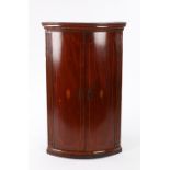 George III mahogany and marquetry inlaid bow front hanging corner cupboard, the bow front doors with