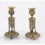 Pair of 19th Century decorative candlesticks, the sconces above a figure base on three legs and