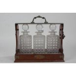 Victorian Betjemann's patent tantalus oak and cut glass tantalus, housed three decanters to the