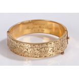Gold plated bangle, the body with scroll and foliate decoration to one half, the interior stamped
