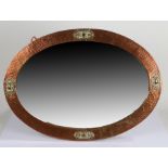 Arts and Crafts copper and brass mirror, of oval shape, with spot hammered copper frame with oval