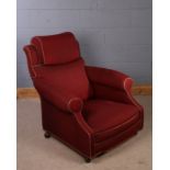 Howard & Sons type armchair, upholstered in burgundy, with padded head rest and deep seat, raised on