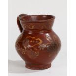 An English slipware red stoneware jug, with flower design, 14cm