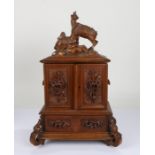 19th Century Black Forest table cabinet, the carved top depicting two chamois above two cupboard