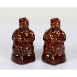 Pair of 19th Century treacle glazed figural money boxes, modelled as a seated figure holding a