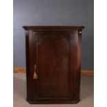 George III oak hanging corner cupboard, the panelled door opening to reveal three shaped front