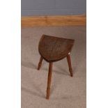 20th Century carved oak stool, the shield shaped seat carved with a crest, raised on three tuned