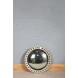A painted convex mirror, the cream frame having black inner slip and ebonised ball decoration,