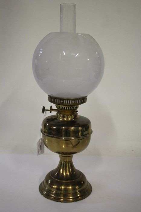 Duplex oil lamp, with frosted white globe and clear glass chimney above a brass reservoir, waisted