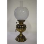 Duplex oil lamp, with frosted white globe and clear glass chimney above a brass reservoir, waisted