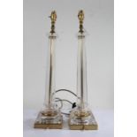 Pair of moulded glass column table lamps, the octagonal clear glass columns on square brass bases,