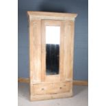 Victorian stripped pine wardrobe, the cornice above a single mirrored door enclosing brass hooks,