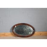 Edwardian oak framed wall mirror, the bevelled mirror plate housed in an oval bead carved frame,