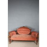 Late Victorian walnut settee, the button back with a crested rail above padded arms, raised on