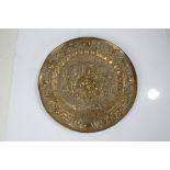 Embossed brass charger with central tavern scene and foliate border, 43.5cm diameter