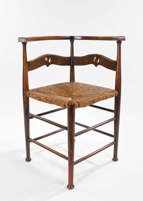 Arts and Crafts corner chair, the curved cresting rail above a pierced splat back and cane seat,