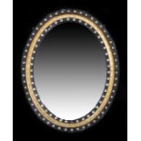 Early 19th century Irish oval wall mirror, the ebonised and gilt frame decorated and gilded with cut