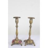 Pair of brass candlesticks, with knob and turned stems above a square base and paw feet, 21cm high