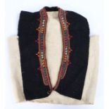 Greek waistcoat, with a colourful red, orange, white and green trim to the black and cream coat.