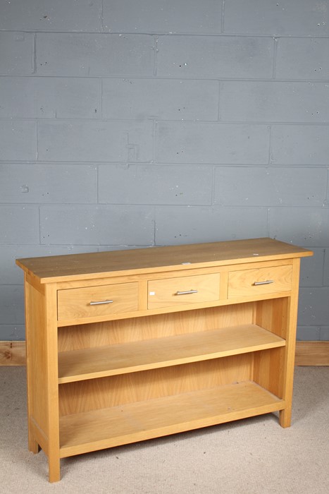 Light oak sideboard, the rectangular top with three frieze drawers, above an open shelf, raised on