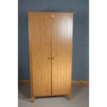 Pair of light oak wardrobes, with hinged doors opening to reveal a single shelf and a rail, 191cm