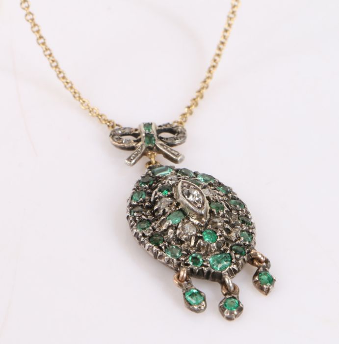 Emerald and diamond set pendant, the tied ribbon pediment above an oval body set with emeralds and