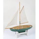 Model of a sailing Yacht, with a single mast painted green on a stand