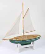 Model of a sailing Yacht, with a single mast painted green on a stand