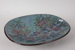 Chelsea Pottery, a large shallow dish, decorated flowers on a turquoise ground, raised on four feet,
