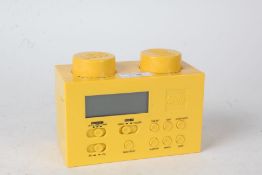 Lego portable clock radio, in the form of a yellow brick, with charger, 16cm wide and 11.5cm high