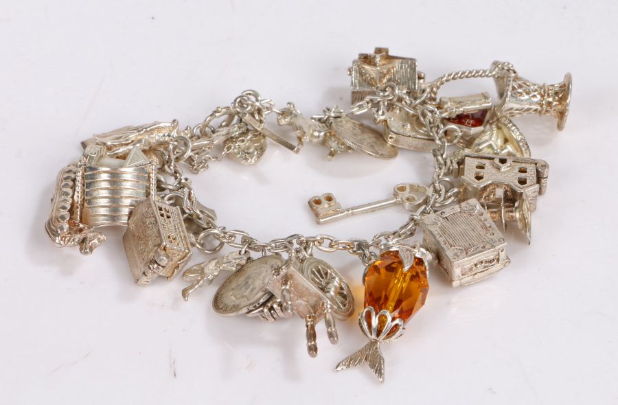 Silver charm bracelet, to include three pence piece, Canadian five cents and various other charms