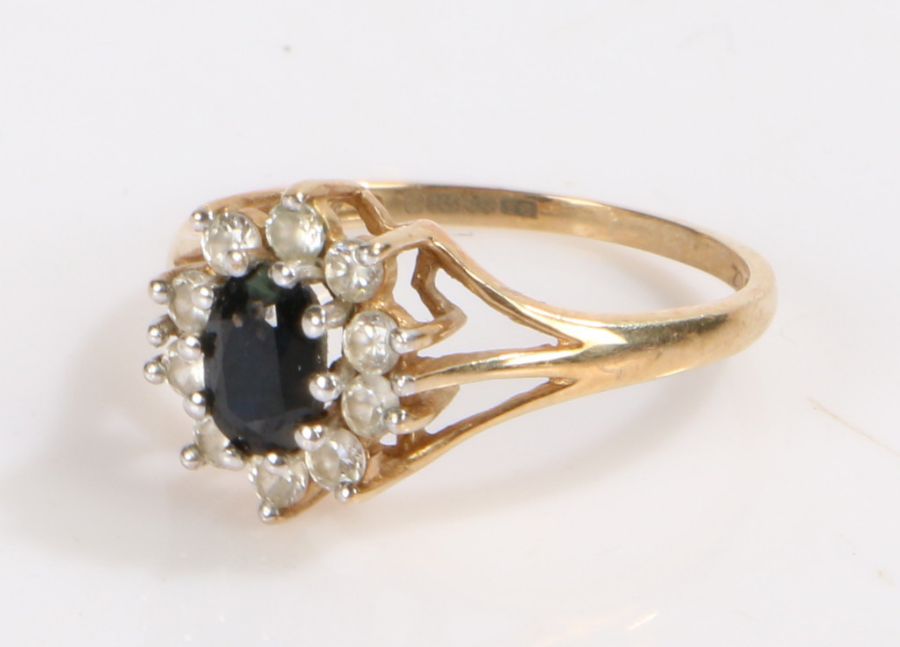 9 carat gold ring set with a central blue stone surrounded by clear paste, ring size M, 1.8g