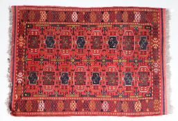 Modern Afghan rug, the red ground with elephant foot lozenge pattern centre and tasselled ends,