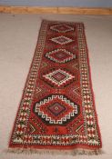 Eastern runner, centred with octagonal medallions on a red field, 279cm x 80cm