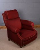 Howard & Sons type armchair, upholstered in burgundy, with padded head rest and deep seat, raised on