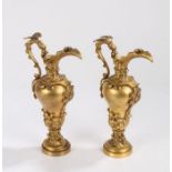 Pair of 19th Century gilt bronze ewers, with dragon capped handles to the scroll decorated spouts,