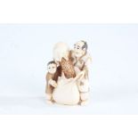 Japanese Meiji period carved ivory netsuke, in the form of a man and boy pouring grain into a
